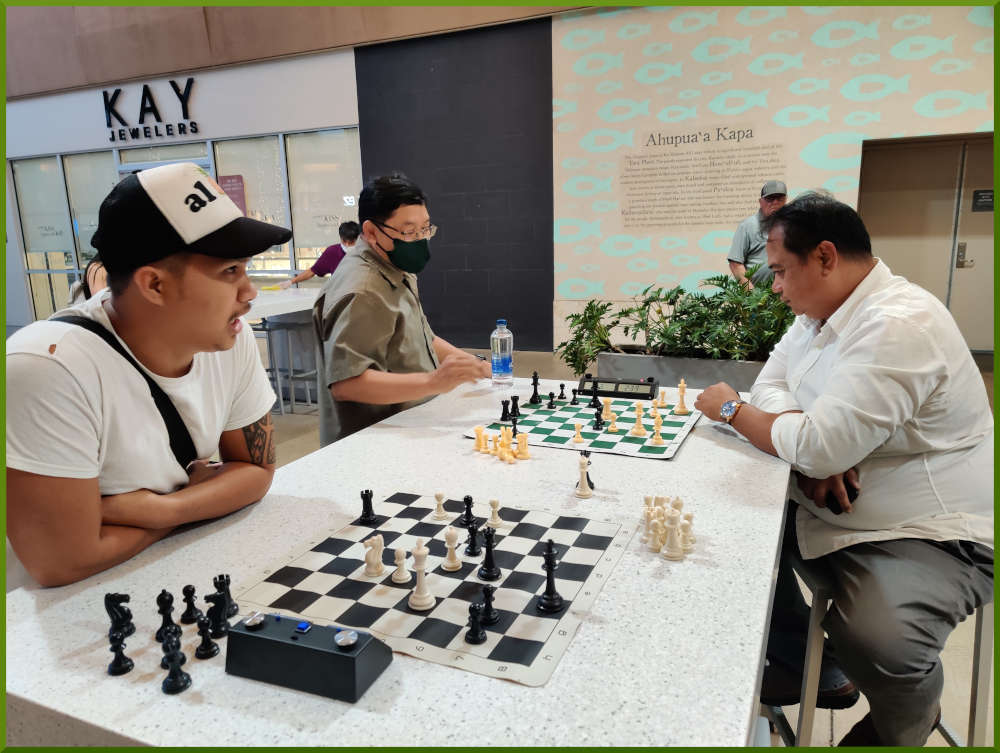 April 19th, 2022. Ka Makana Alii chess meetup. Shane waits for a new player (near board). Jose vs Richard (far board).
